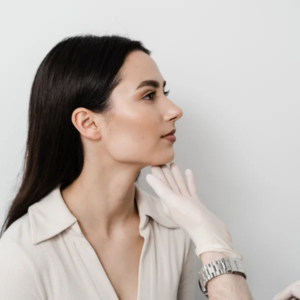 Une femme reçoit un soin du visage par un médecin dans un cadre clinique, avec des équipements de soins de la peau visibles.