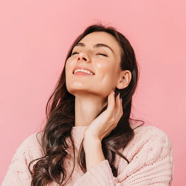 Une femme souriante regarde la caméra, mettant en avant l'importance du collagène pour la peau.