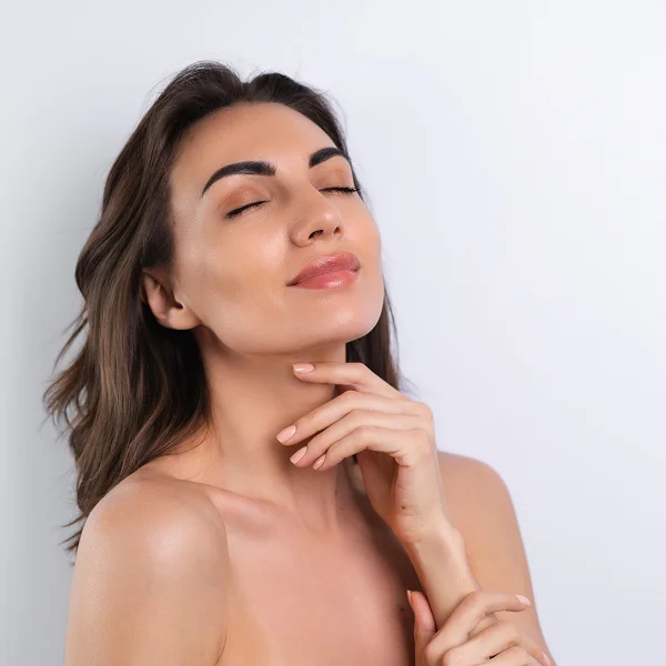 Femme belle avec peau nette et yeux fermés sur fond blanc, évoquant l'utilisation de collagène pour la peau.