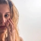 Une femme se regarde dans le miroir, examinant son visage avec une expression préoccupée.
