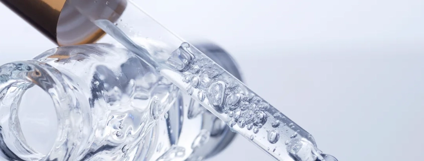 Une bouteille en verre avec un liquide, de l'acide hyaluronique, en cours de versement.