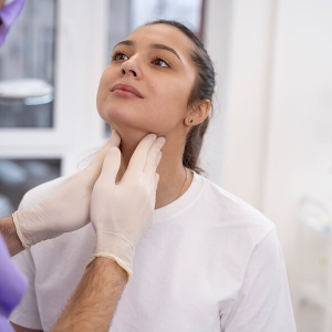Une femme se fait examiner le cou par un médecin.