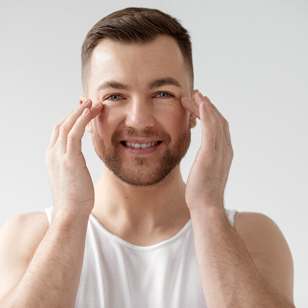 Un homme se tient les mains sur le visage, illustrant le concept de soin esthétique du visage.