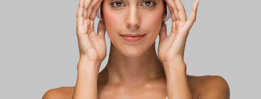 Une femme avec une serviette sur la tête, symbolisant le soin esthétique du visage pour un aspect reposé et naturel.