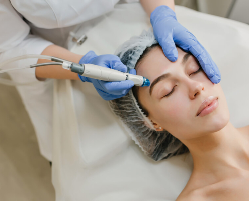 Une femme reçoit un soin du visage dans un salon de beauté, détendue sur une table de traitement.