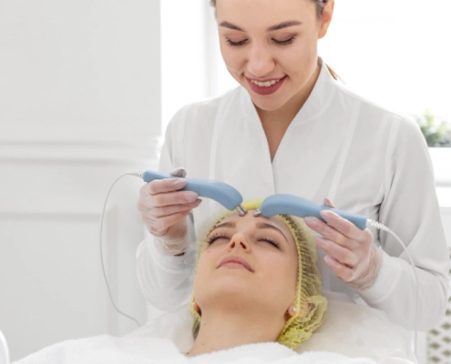 Une femme reçoit un soin du visage avec un appareil esthétique dans un cadre relaxant.